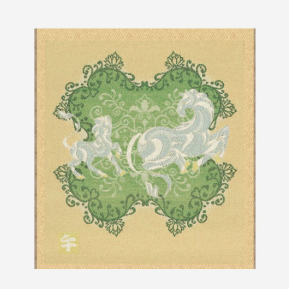 幸運の意味を持つ四つ葉のクローバーが広がる草原で、白馬の親子が戯れている様子を描いています