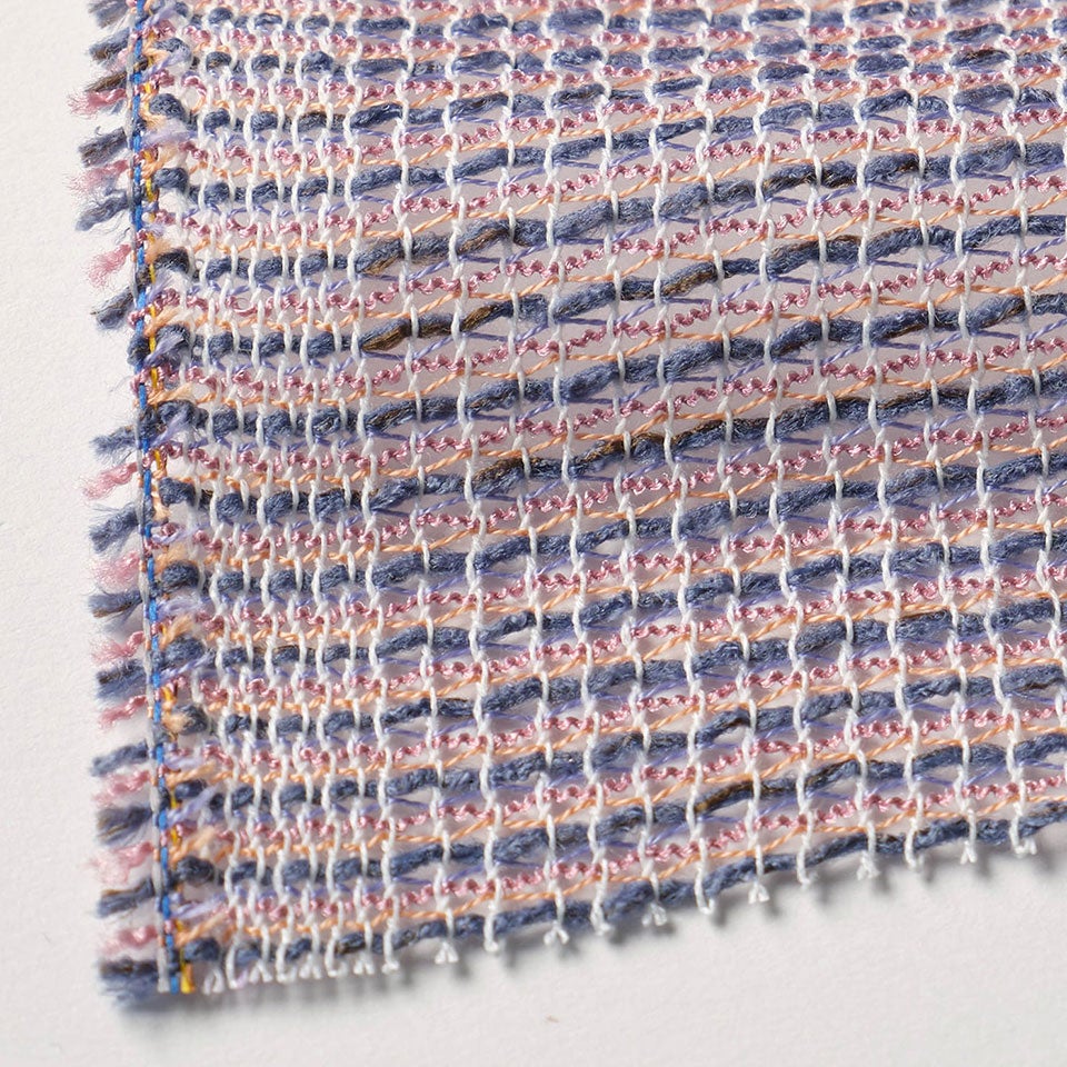 生地拡大画像／ふわりとした再生素材の糸や自社で手作りしたくるくるとした糸を、ダイヤ型に絡めるように織り上げ「懐かしさ」を表現しました